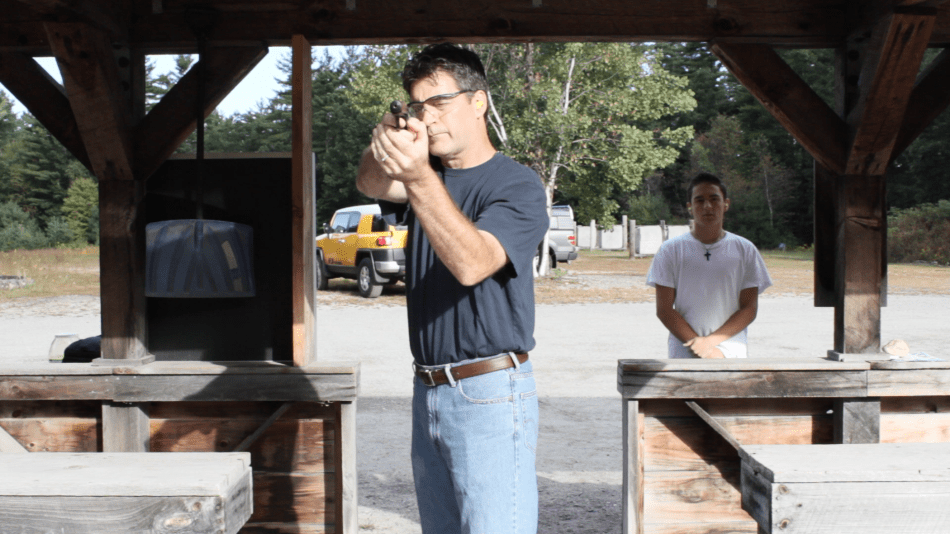 Henri Miller practices at the shooting range. His son Gary looks on.
